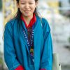 A young woman outdoors in vibrant traditional attire, smiling warmly.